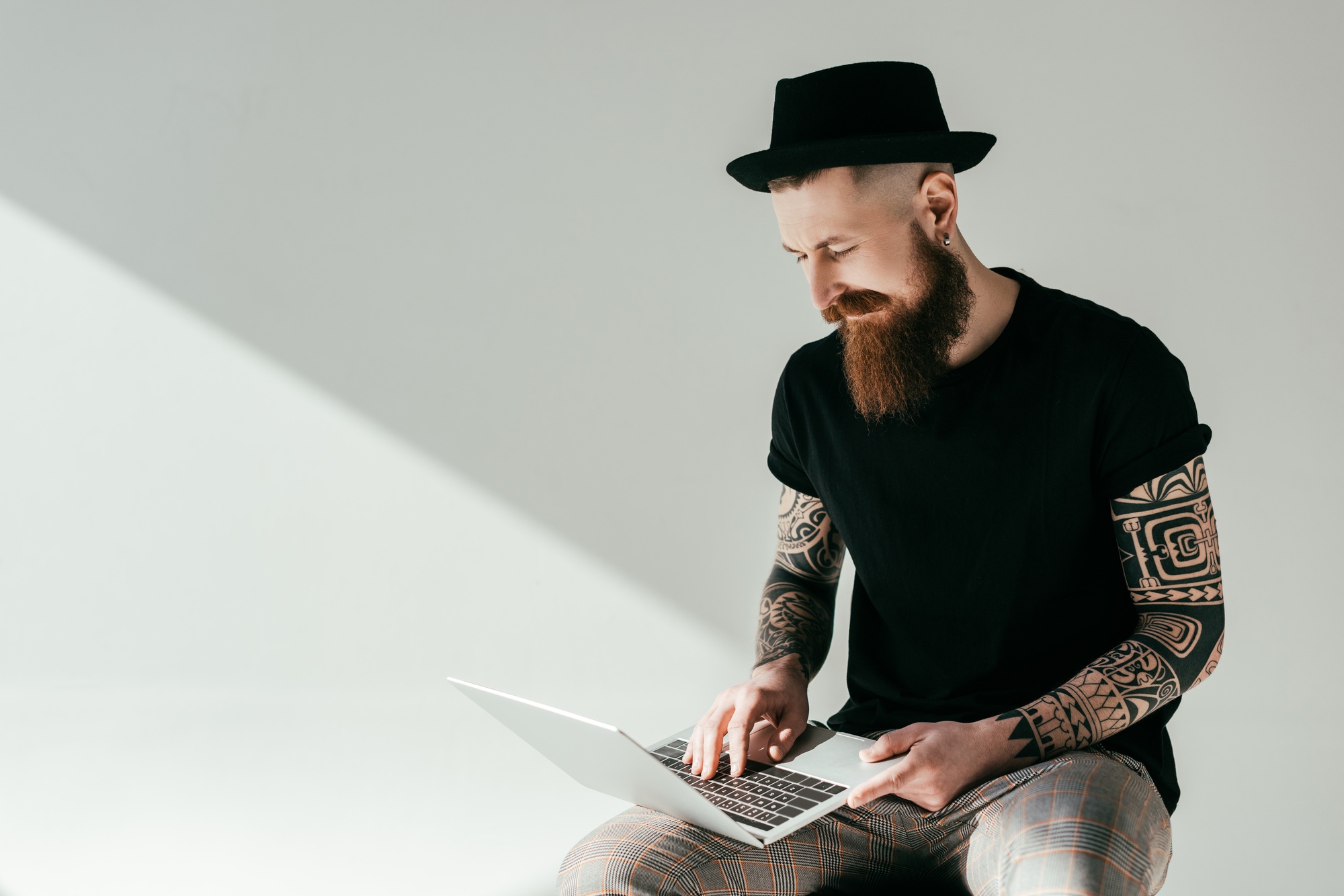 handsome bearded tattooed man looking at laptop on white handsome bearded tattooed man looking at laptop on white