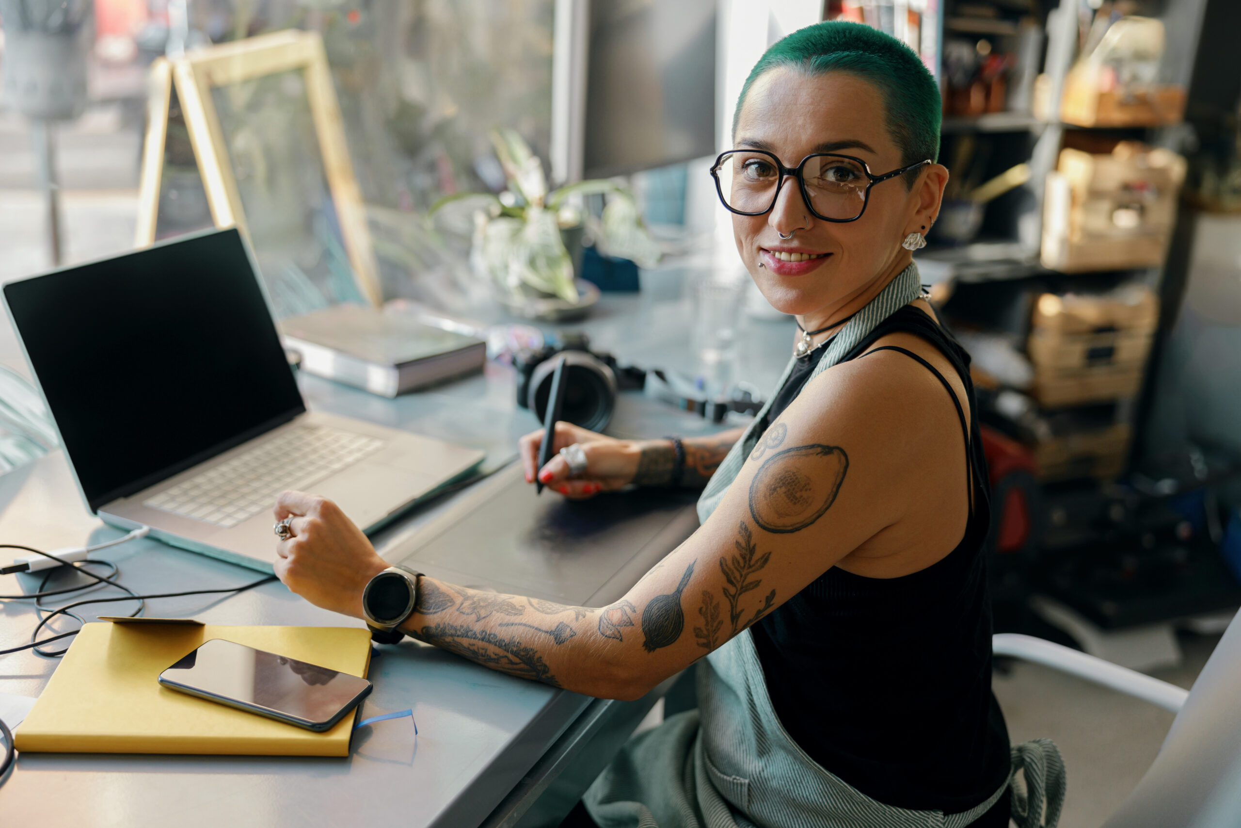 Female worker uses graphics tablet and laptop for retouching photos or digital drawing in studio Two beautiful girls at tattoo studio