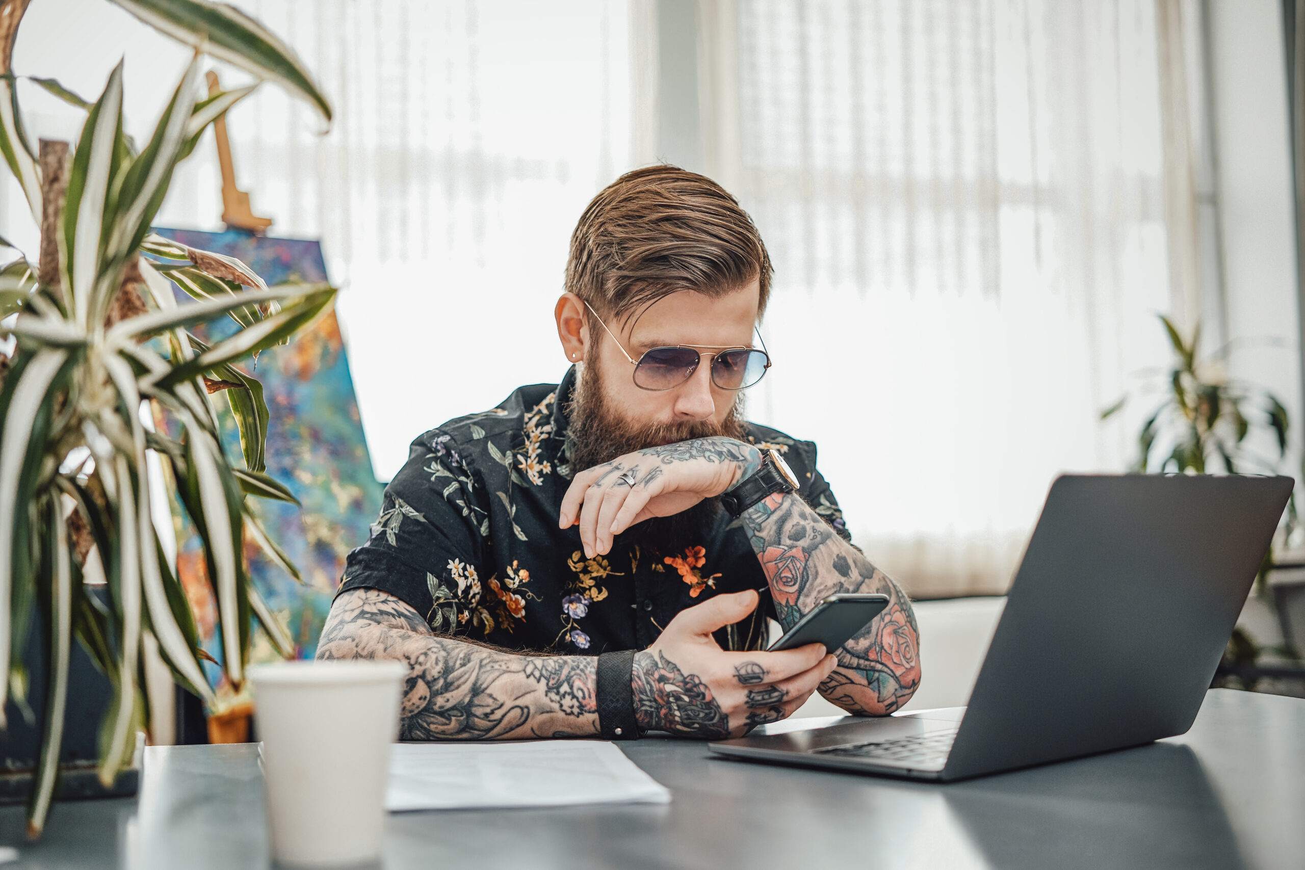 Serious businessperson with sunglasses and smartphone Beautiful interior of tattoo master workplace in modern studio